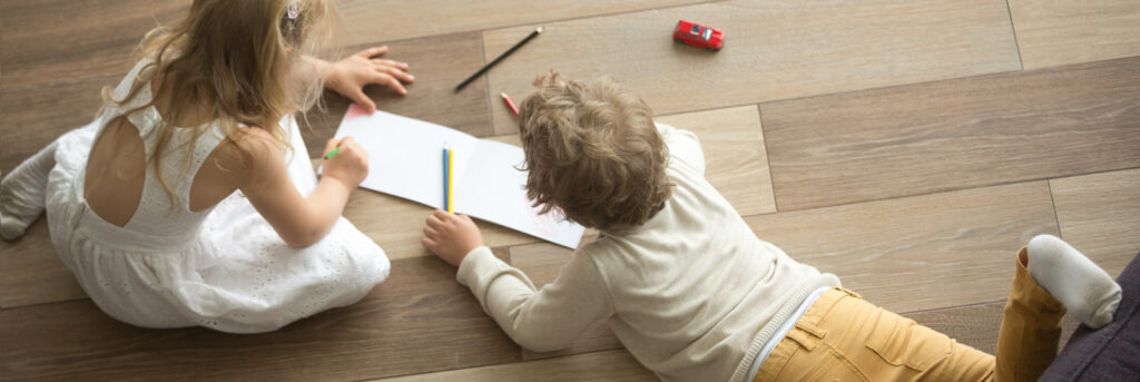 ein Junge und ein Mädchen liegen auf dem Fußboden und malen